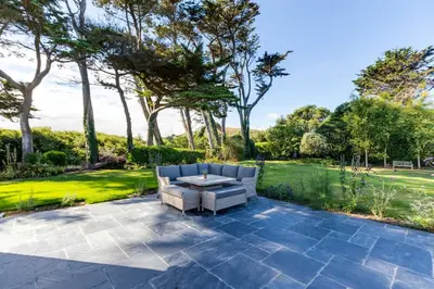 a patio with a couch and a table and trees at Greystones in Polzeath
