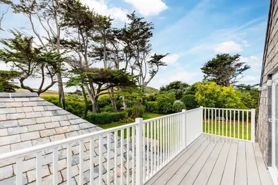 a balcony with a white fence and trees at Greystones in Polzeath
