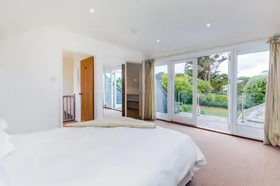 a bedroom with a large bed and large windows at Greystones in Polzeath