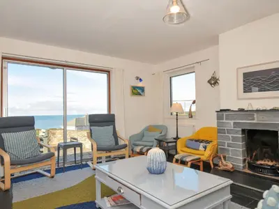 a living room with a fireplace and a view of the ocean at Upper Gren in Polzeath
