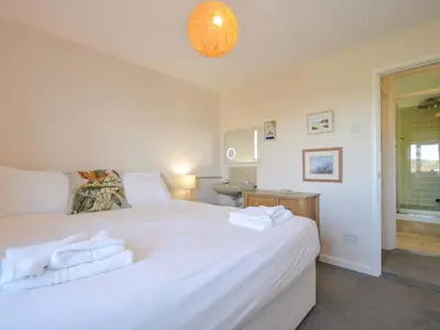 a bedroom with a large white bed with towels on it at Upper Gren in Polzeath