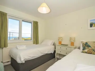 two beds in a room with a window at Upper Gren in Polzeath