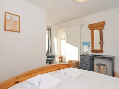 a bedroom with a white bed and a chair at Upper Gren in Polzeath