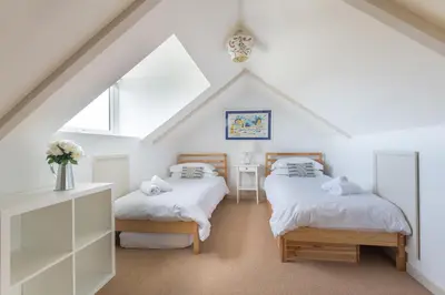 a attic bedroom with two beds and a window at Westray House in Polzeath