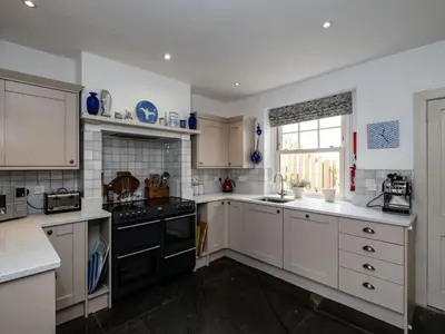 a kitchen with white cabinets and a black stove top oven at Westray House in Polzeath