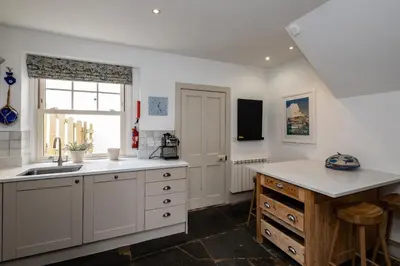 a kitchen with white cabinets and a sink and a window at Westray House in Polzeath