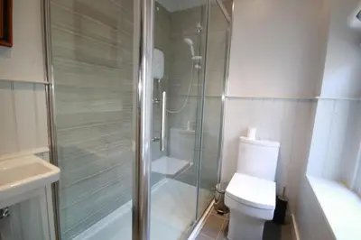 a bathroom with a shower and a toilet and a sink at Westray House in Polzeath