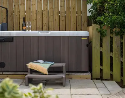 a bench with a hot tub next to a fence at Westray House in Polzeath