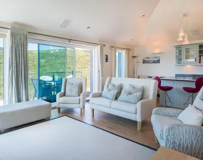 a living room with two white couches and a kitchen at Egloskerry in Wadebridge