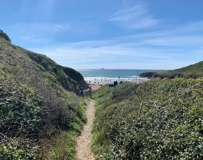 a dirt path leading to a beach with people on it at Egloskerry in Wadebridge
