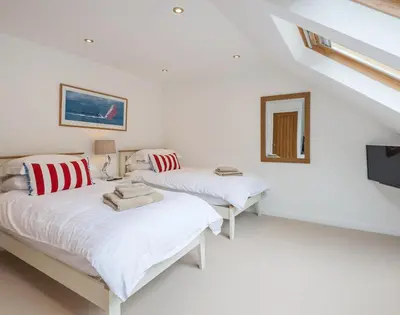 a white room with two beds and a television at Upper Deck in Padstow