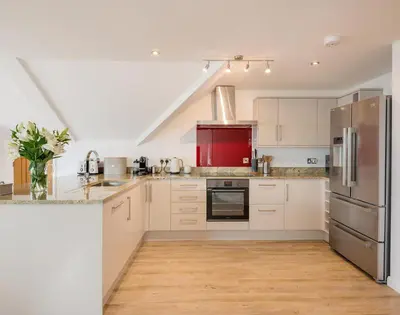 a kitchen with white cabinets and stainless steel appliances at Upper Deck in Padstow
