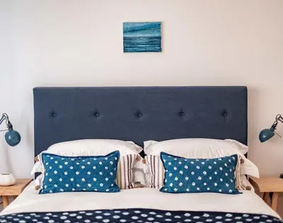 a bed with a blue head board with pillows at Seastar in Wadebridge