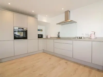 a kitchen with white cabinets and a wooden floor at Gwel Nans in St. Agnes