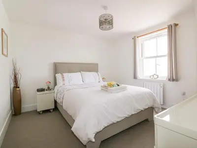 a white bedroom with a bed and a window at Gwel Nans in St. Agnes