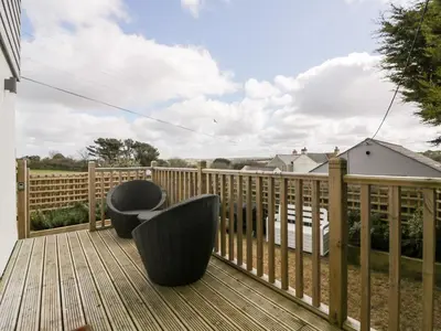 two chairs sitting on a deck with a fence at Gwel Nans in St. Agnes