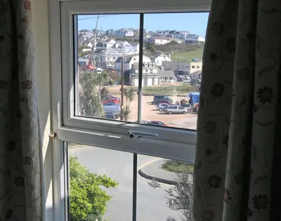 an open window with a view of a city at Coppingers Cottage in Polzeath