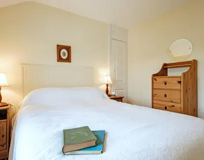a bedroom with a white bed with a book on it at Coppingers Cottage in Polzeath