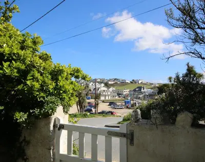 a view of a white fence and a street at Coppingers Cottage in Polzeath