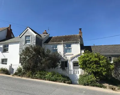 a white house sitting on the side of a street at Coppingers Cottage in Polzeath