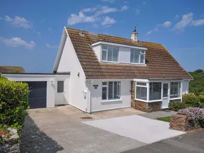 a white house with a brown roof and a garage at Sunset in Polzeath