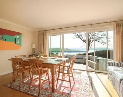 a dining room with a table and chairs and a large window at Little Strand in Padstow