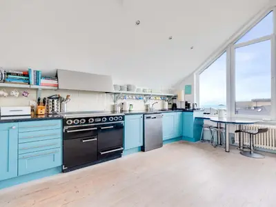 a large kitchen with blue cabinets and a table at The Point in Polzeath