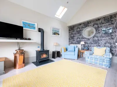 a living room with a wood stove and two chairs at The Point in Polzeath