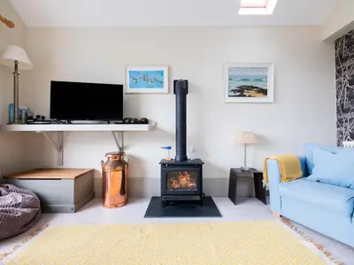 a living room with a fireplace and a blue couch at The Point in Polzeath