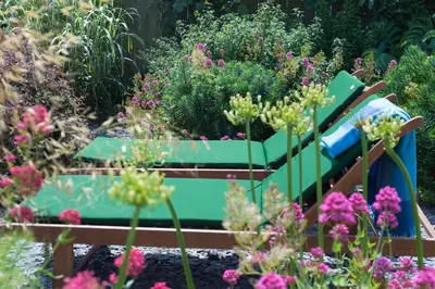 a green bench in a garden with flowers at The Point in Polzeath