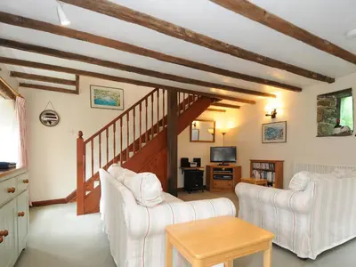a living room with two white chairs and a table at The Granary in Saint Minver