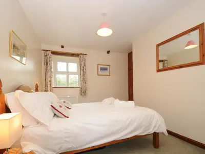 a bedroom with a bed with white sheets and a window at The Granary in Saint Minver