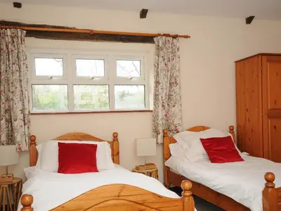 two beds in a bedroom with a window at The Granary in Saint Minver