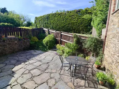 a patio with a table and chairs and a fence at The Granary in Saint Minver