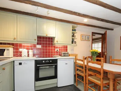 a kitchen with white cabinets and a table with chairs at The Granary in Saint Minver
