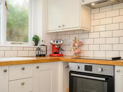 a kitchen with white cabinets and a red appliance at Trevega in Polzeath