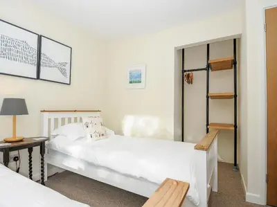a bedroom with two white beds and a table and a lamp at Trevega in Polzeath