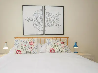 a bedroom with a white bed with two pictures on the wall at Trevega in Polzeath