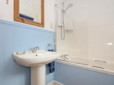 a white bathroom with a sink and a shower at Trevega in Polzeath