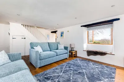 a living room with a blue couch and a window at Dingles Cottage in Saint Minver