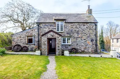 an old stone house with a grass yard at Dingles Cottage in Saint Minver