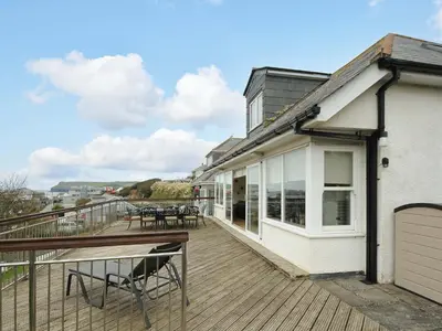 a deck with tables and chairs on a house at Pendaveli in Polzeath