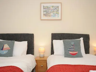 a bedroom with two beds and a picture of a boat pillow at Pendaveli in Polzeath