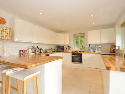 a kitchen with white cabinets and wooden counter tops at The Old Granary in Saint Minver