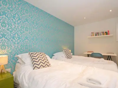 a bedroom with two beds and a blue wall at The Old Granary in Saint Minver