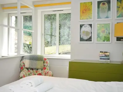 a bedroom with a bed and a chair and windows at The Old Granary in Saint Minver