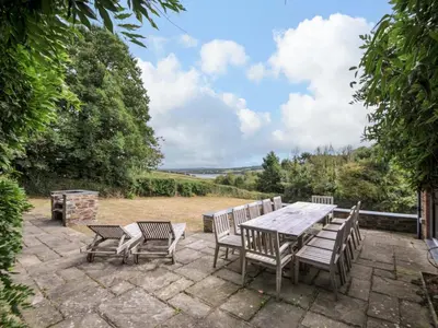 a table and chairs on a patio with a view at The Old Granary in Saint Minver