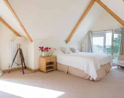 a white bedroom with a bed and a window at Ragleighs in Polzeath
