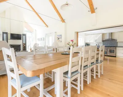 a kitchen and dining room with a wooden table and chairs at Ragleighs in Polzeath