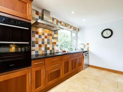 a kitchen with wooden cabinets and a clock on the wall at Longhouse Bungalow in Polzeath